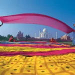 Viaje a India y Nepal. La imagen muestra el Taj Mahal, un majestuoso mausoleo de mármol blanco ubicado en Agra, Uttar Pradesh, India. Construido entre 1631 y 1648 por el emperador mogol Shah Jahan en memoria de su esposa Mumtaz Mahal, el Taj Mahal es reconocido por su impresionante arquitectura que combina elementos islámicos, persas, indios e incluso turcos. Este monumento es Patrimonio de la Humanidad por la UNESCO desde 1983 y fue designado como una de las Nuevas Siete Maravillas del Mundo Moderno en 2007. El complejo incluye, además del mausoleo principal, una mezquita, una casa de invitados y extensos jardines que se extienden a lo largo de 17 hectáreas.